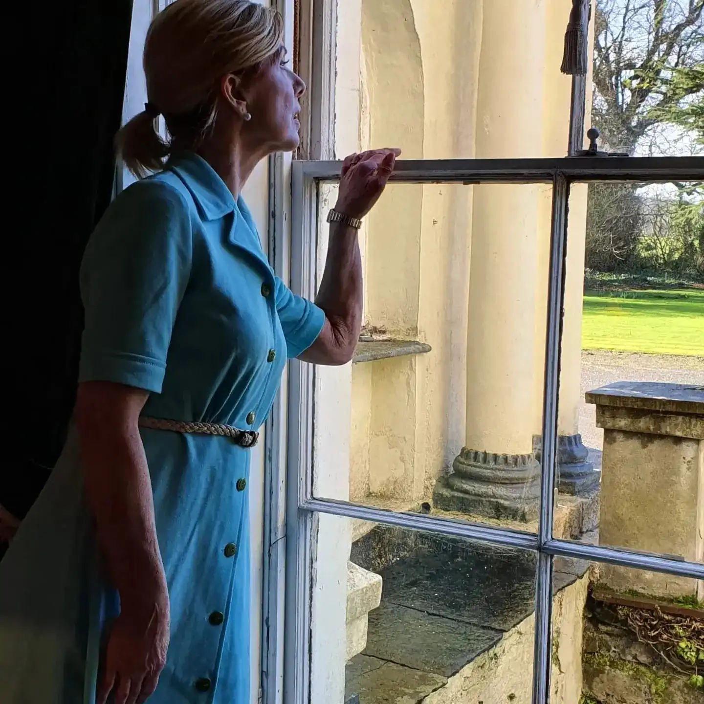 Joan looking out of a window in period costume