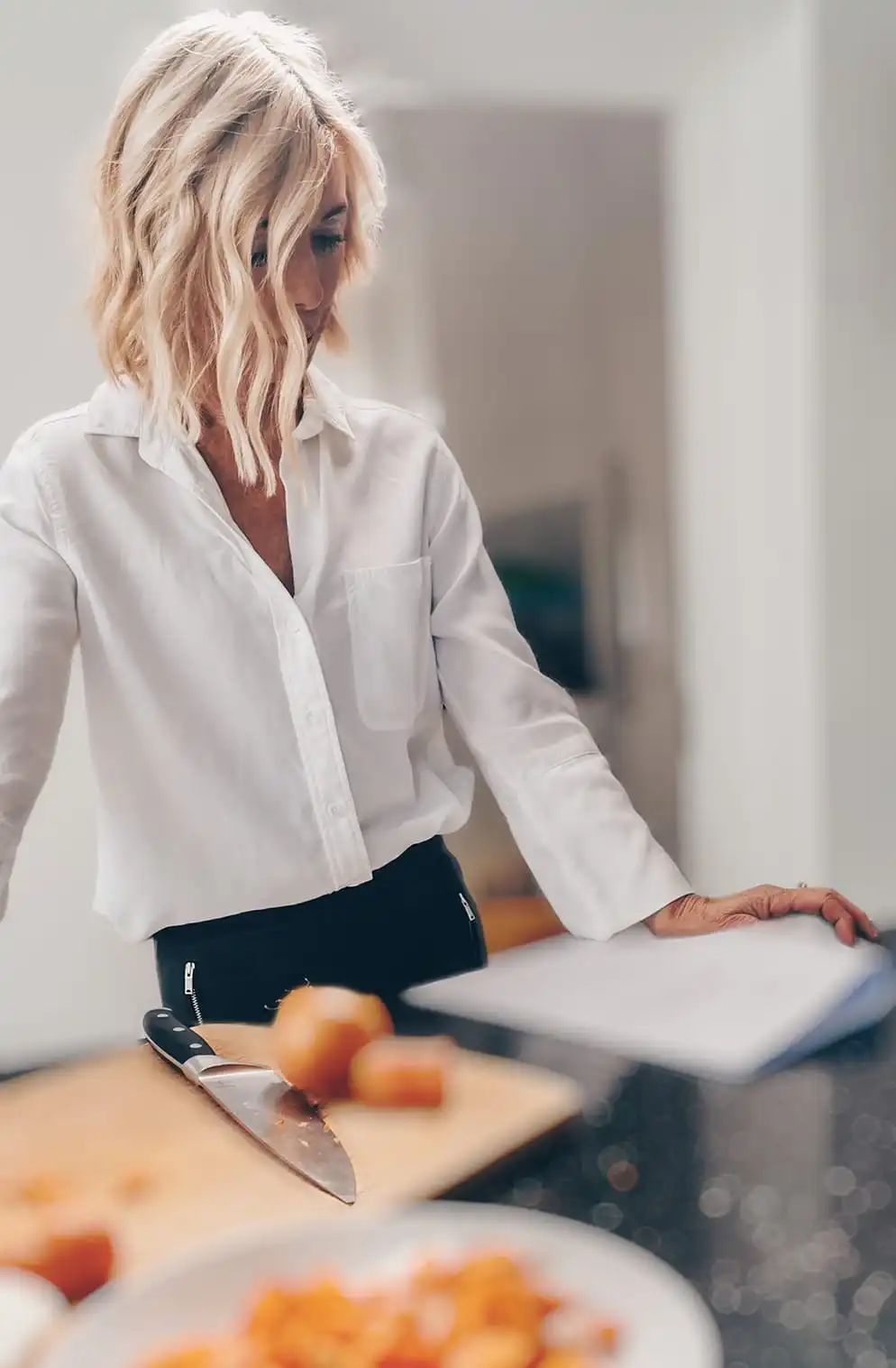 Joan in a scene from Matriarch with her hair over her face while chopping vegetables